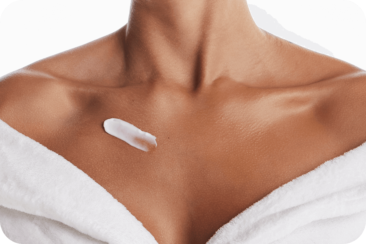 Imagem que destaca o trapézio feminino, vestido com um roupão e uma pincelada de creme acima dos seios, para direcionar os clientes para uma coleção que lista os produtos para o colo corporal.